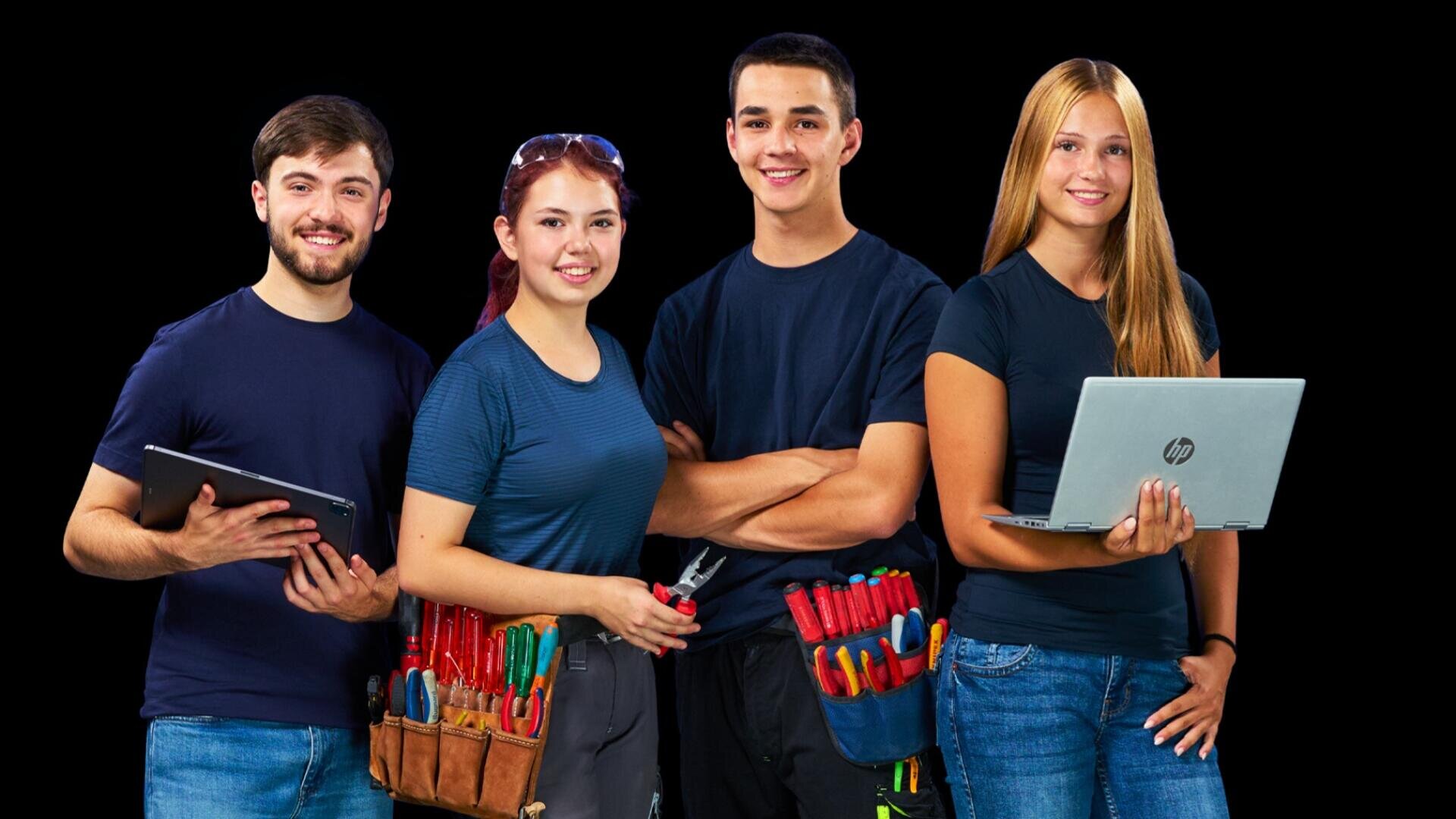 Quatre jeunes adultes – deux hommes et deux femmes – se tiennent debout devant un fond noir, le sourire aux lèvres, avec leurs ordinateurs portables et leurs ceintures à outils remplies d'outils.