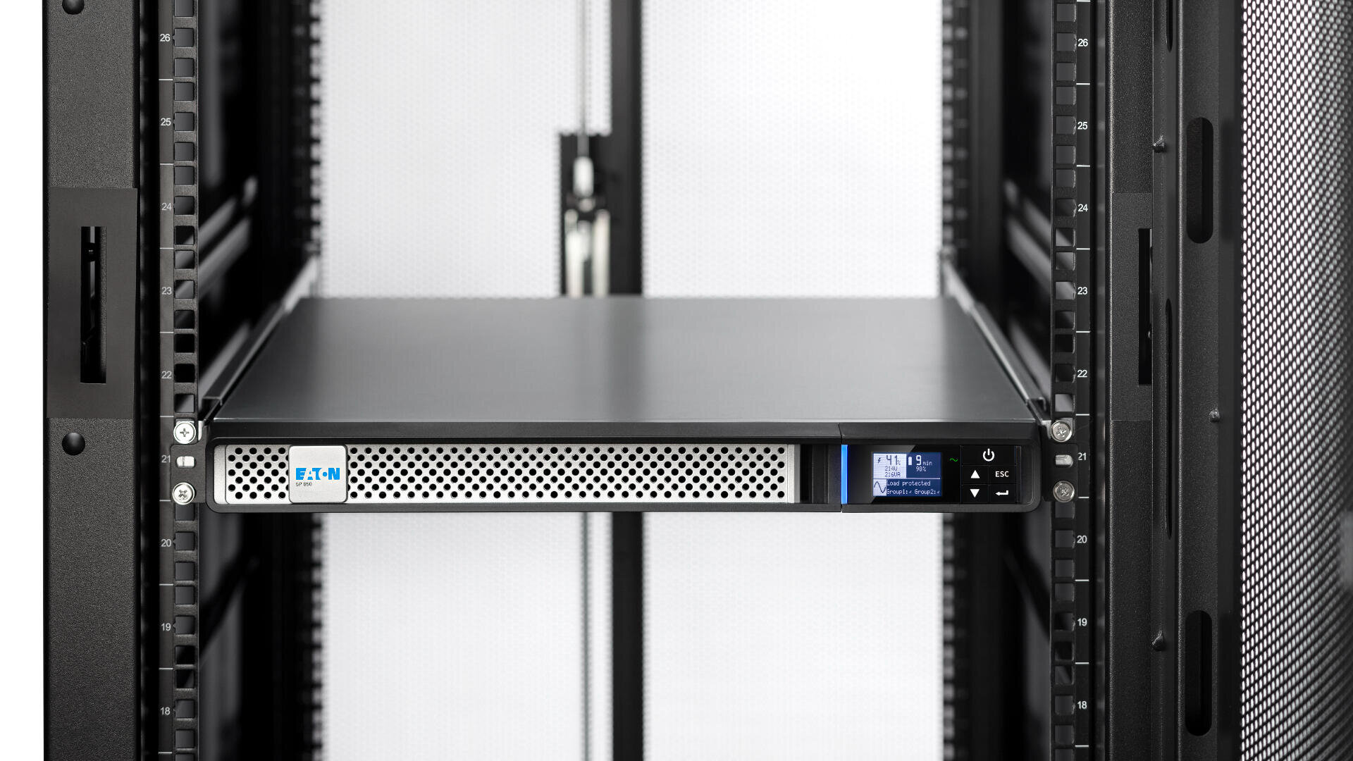 Eine schwarze unterbrechungsfreie Stromversorgungseinheit (USV) von Eaton ist in einem Serverschrank mit Gittertüren installiert, von vorne gesehen. Die USV zeigt einen kleinen digitalen Bildschirm und Steuertasten auf der rechten Seite.