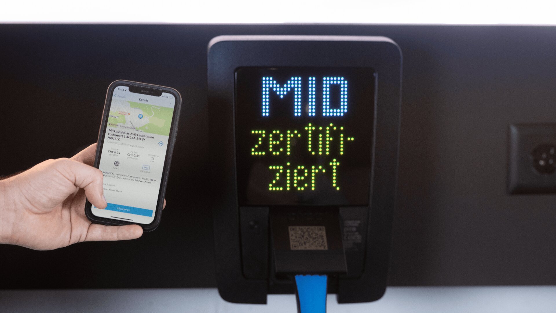 Eine Person hält ein Smartphone mit einer Mobilitäts-App vor einen digitalen Fahrkartenentwerter, auf dessen Bildschirm MIO zertifiziert angezeigt wird. Auf dem Entwerter ist ein QR-Code zu sehen.