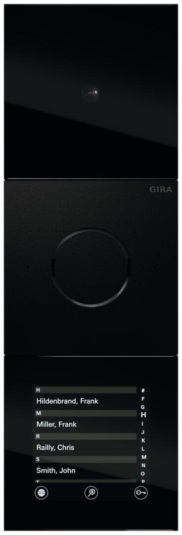 Un panneau de commande d'interphone électronique noir avec une caméra en haut, un bouton rond au milieu et un écran numérique en bas affichant plusieurs noms, avec des icônes de navigation tactile en dessous.