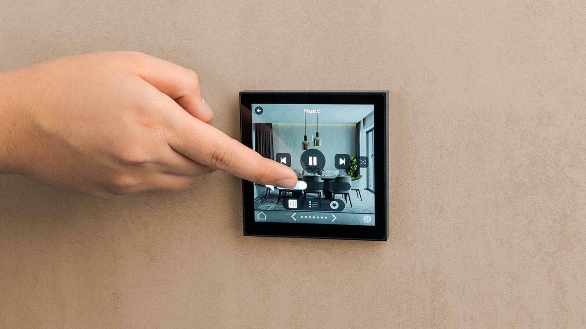 Eine Hand berührt ein an der Wand montiertes Smart-Home-Bedienfeld, das einen Raum und Steuerelemente für die Musikwiedergabe anzeigt, darunter Tasten für Wiedergabe, Pause und Überspringen.