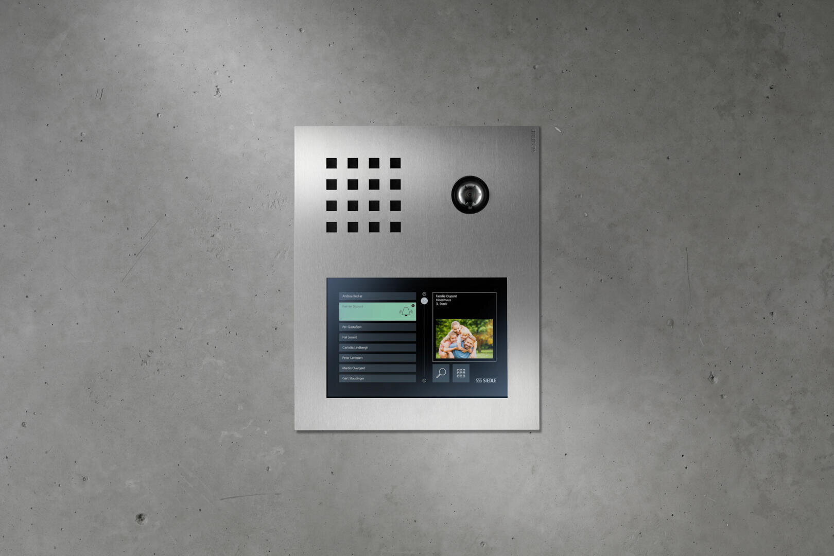 Eine moderne, an der Wand montierte Gegensprechanlage mit Metalloberfläche, ausgestattet mit einem hochwertigen Lautsprechergitter, einem Kameraobjektiv und einem Siedle Touch 10 Farbdisplay, auf dem Menüoptionen sowie ein kleines Bild einer Person angezeigt werden.