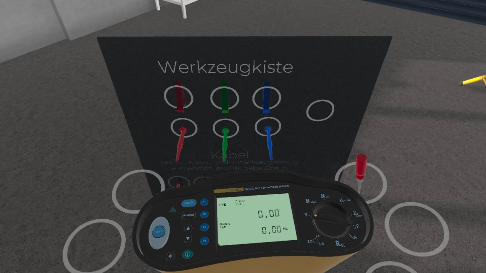 Ein digitales Messgerät mit einem Display, das Nullen anzeigt, befindet sich vor einer Tafel mit der Aufschrift Werkzeugkiste. Die Tafel hat farbige Kabel (rot, grün, blau), die an entsprechende Buchsen angeschlossen sind.