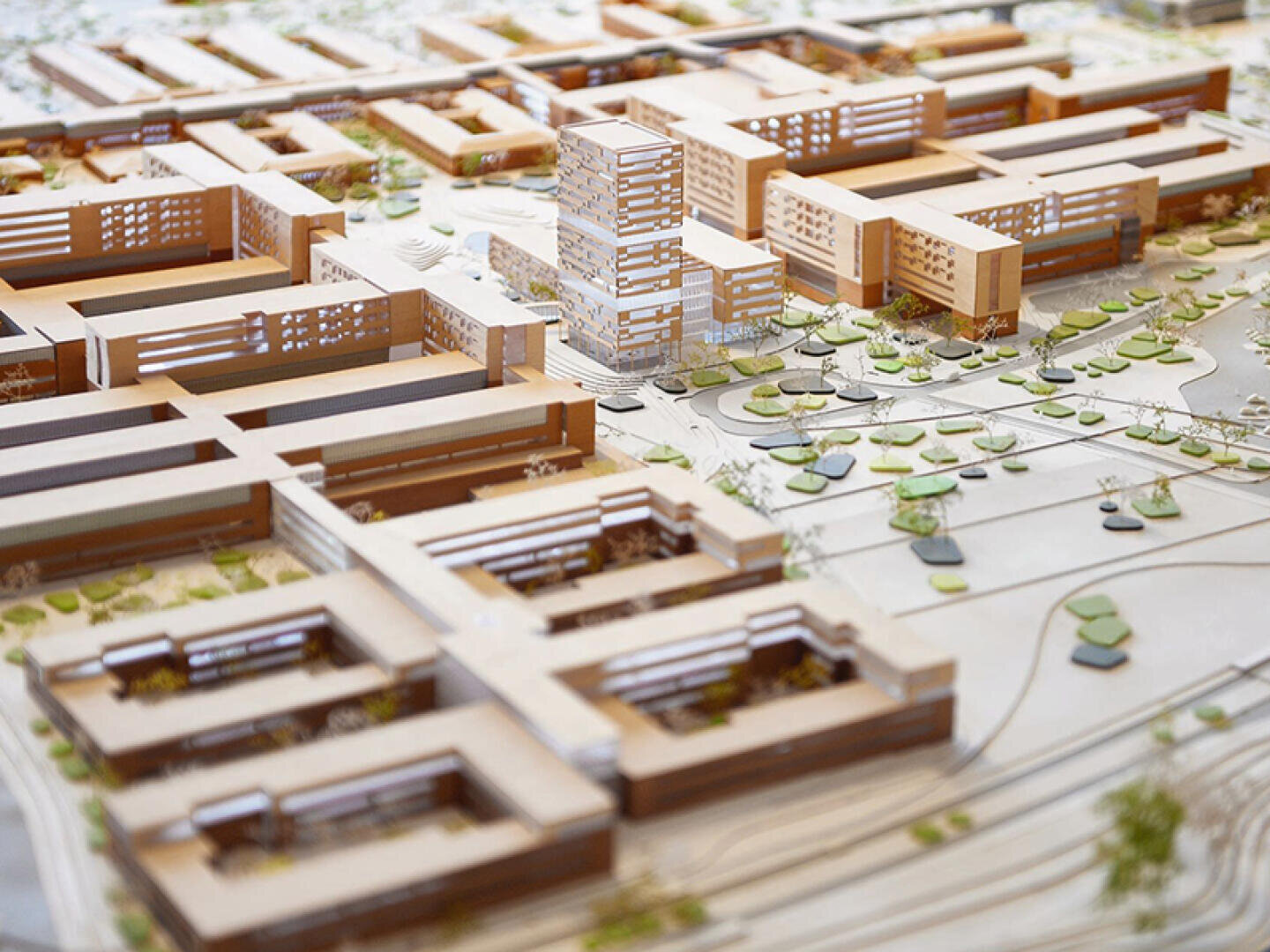 Une maquette architecturale détaillée présente des bâtiments modernes, des espaces verts, des allées et des rues, illustrant ainsi un projet d'aménagement urbain ou le plan d'un campus.