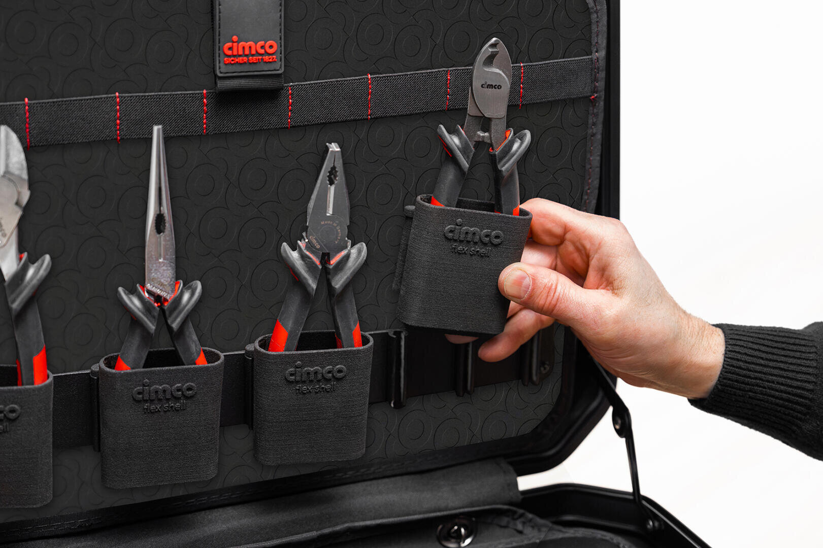 Une main sort une pince d'une boîte à outils noire, dans laquelle se trouvent plusieurs pinces rangées dans des compartiments individuels, tous portant l'inscription « Cimco ».