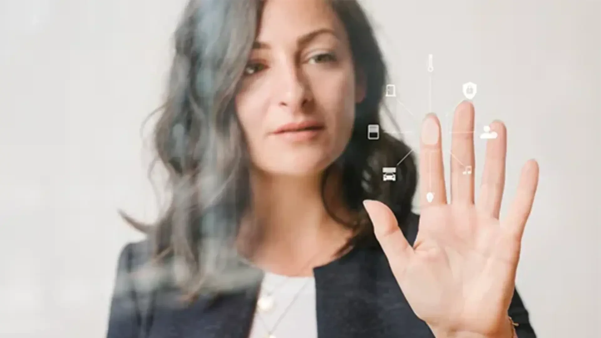 Une femme aux cheveux ondulés touche un écran transparent affichant des icônes numériques, suggérant une interaction avec une technologie futuriste ou virtuelle.