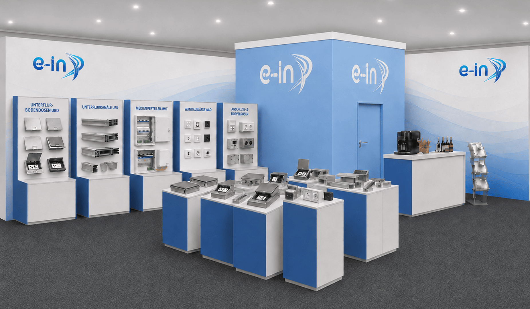 Messestand mit blau-weißem Branding, auf dessen Regalen und Tischen elektronische Geräte und Komponenten ausgestellt sind. Auf der rechten Seite befindet sich eine Theke mit Kaffeemaschinen und Getränken. An den Wänden ist das Logo „e-in“ zu sehen.