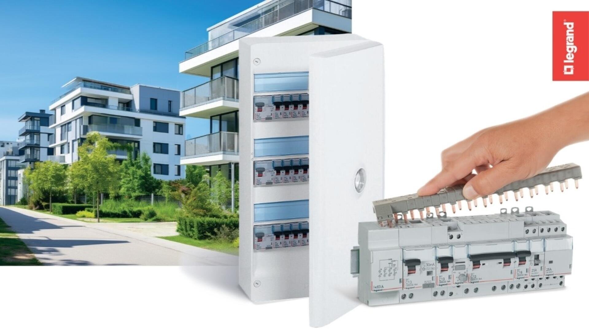 Une main installe une barre conductrice sur les disjoncteurs d'un tableau électrique. En arrière-plan, on voit des immeubles d'habitation modernes et des espaces verts, et à droite le logo Legrand.
