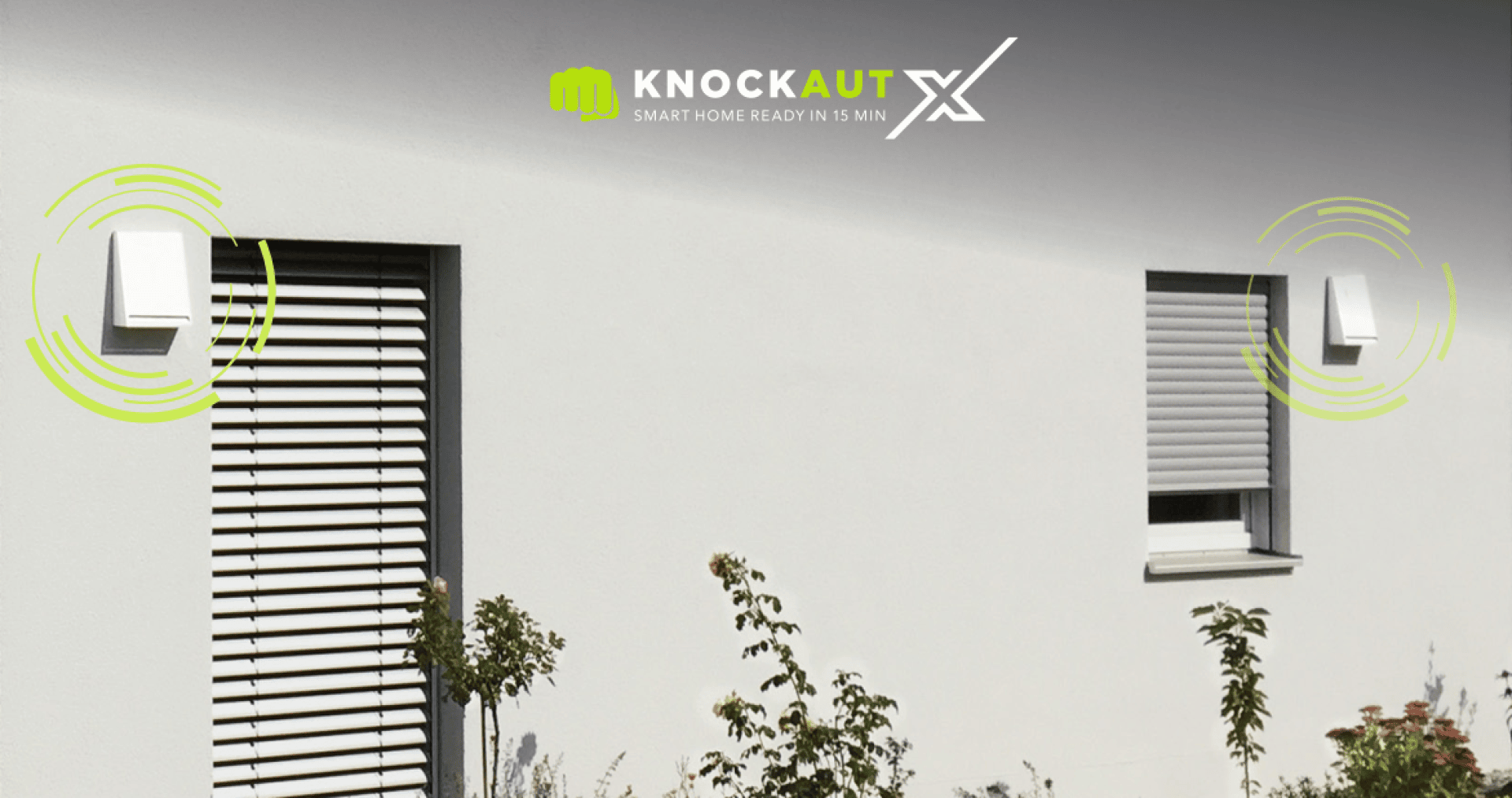 Eine weiße Gebäudefassade mit zwei Fenstern, die beide mit Rollläden abgedeckt sind. Neben jedem Fenster sind elektronische Geräte angebracht, deren grüne Grafiksignale die drahtlose Konnektivität anzeigen. Oben erscheinen das Logo und der Slogan von Knockaut X.