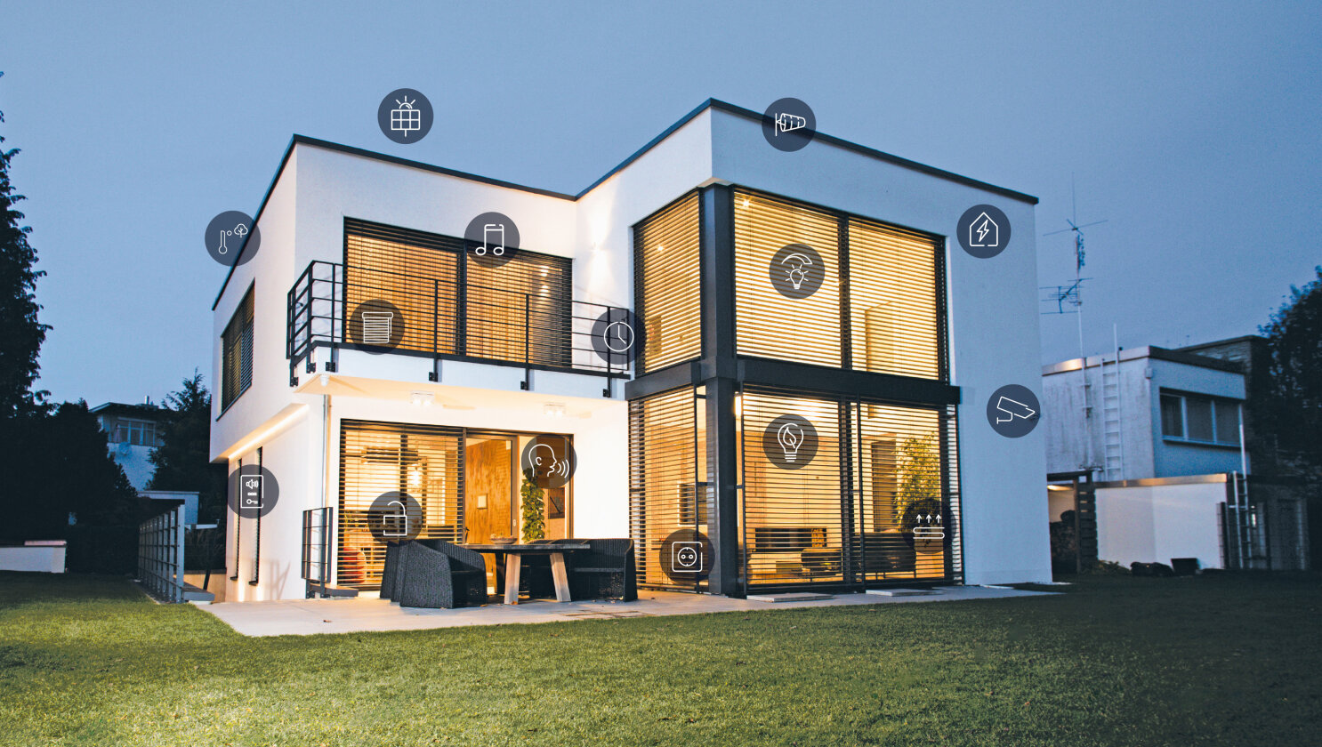 Maison moderne à deux étages au crépuscule, avec de grandes fenêtres, des lumières intérieures allumées et diverses icônes « maison connectée » superposées, représentant les appareils et technologies connectés à l'intérieur et à l'extérieur de la maison.