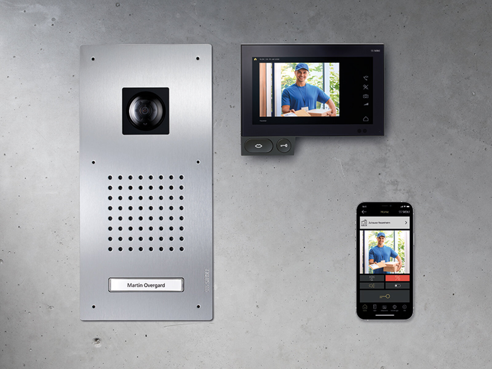 Ein intelligentes Türsprechanlagensystem an der Wand besteht aus einem silbernen Türklingel-Kamerapanel, einem an der Wand montierten Videomonitor, auf dem die Person vor der Tür zu sehen ist, und einem Smartphone, auf dem derselbe Kamerabildausschnitt angezeigt wird.